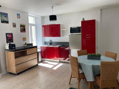 a kitchen with red cabinets and a table with chairs at Appartement au coeur de la vieille ville in Boulogne-sur-Mer