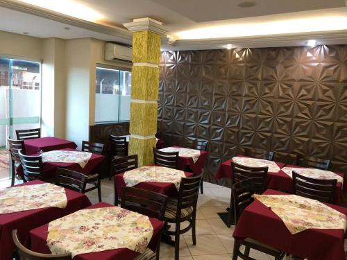 a dining room with tables and chairs with red tablecloths at Nioja Hotel in Itumbiara