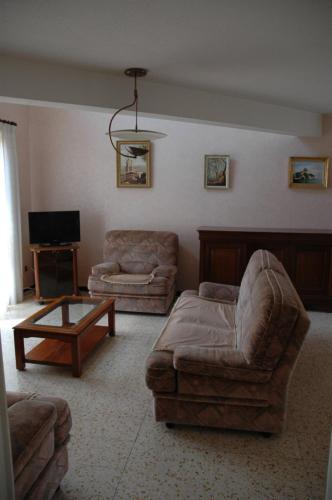 a living room with a couch and a chair and a table at Maison individuelle au calme in Canet-en-Roussillon
