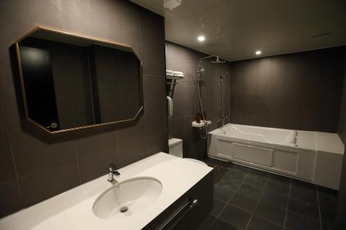 a bathroom with a sink and a bath tub at Forest 701 Hotel in Daegu