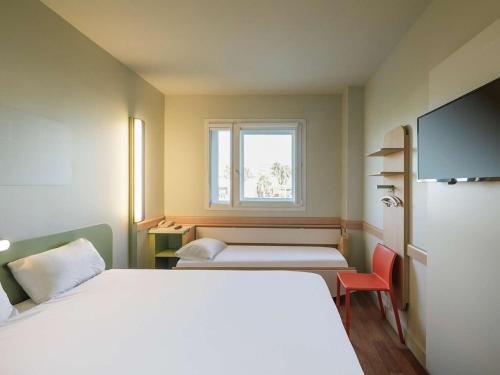 mały pokój z łóżkiem i oknem w obiekcie Ibis Budget Málaga Aeropuerto Avenida de Velazquez w Maladze