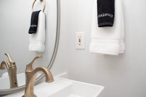 La salle de bains est pourvue d'un lavabo, d'un miroir et de serviettes. dans l'établissement * Midcentury Modern Getaway * Prime Location *, à Annapolis