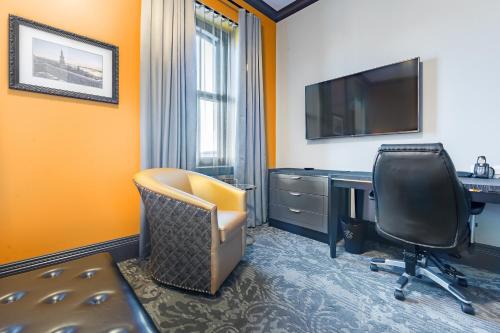 a hotel room with a desk and a chair and a television at Hotel Clarendon in Quebec City