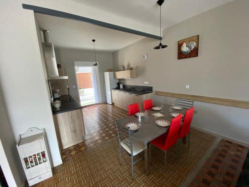 une cuisine et une salle à manger avec une table et des chaises rouges dans l'établissement Le Mazet du Petit Chemin, à Caux