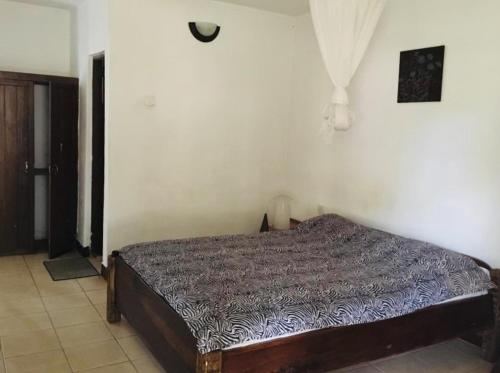 1 dormitorio con 1 cama en una pared blanca en Mama Pierina Restaurant and Annex en Morogoro