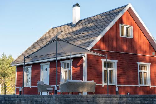a red barn with chairs in front of it at Hundi Holiday Home Main House in Hiiumaa