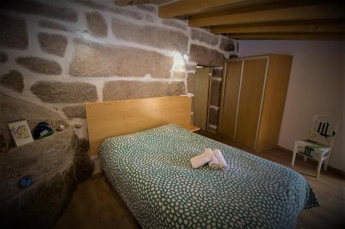 a bedroom with a bed in a room with a stone wall at Beirais do Alvão in Vila Real