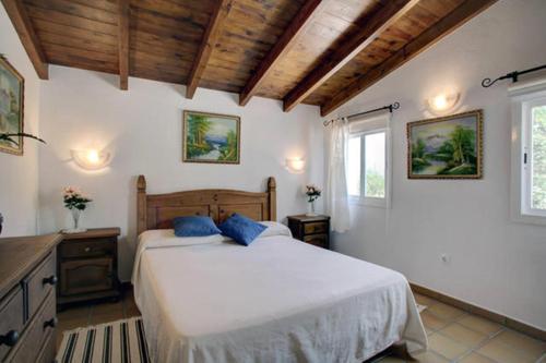 1 dormitorio con 1 cama blanca grande con almohadas azules en Villa Evelyn, en Gaucín