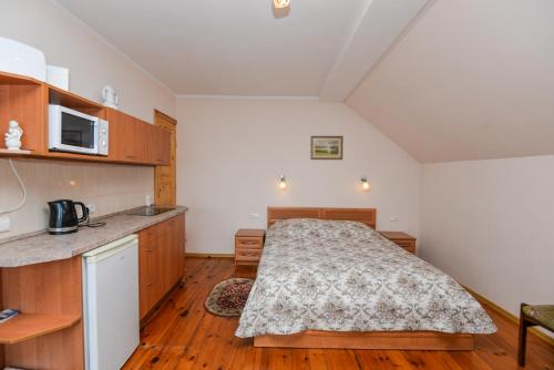 a small bedroom with a bed and a kitchen at Poilsis prie Dineikos parko in Druskininkai