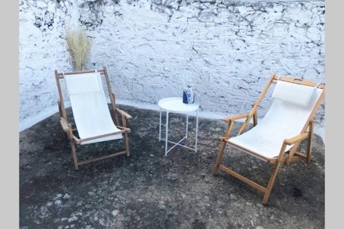 two chairs and a table in front of a wall at Traditional Stone House in Eastern Mani in Flomokhórion