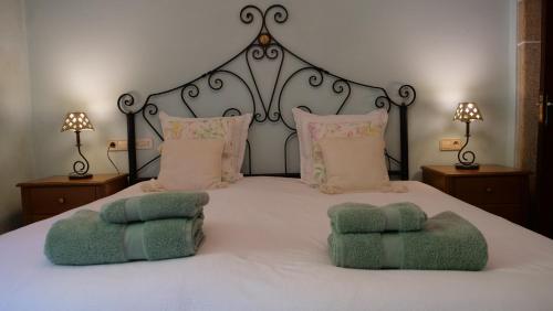 a white bed with two green towels on it at Casa de Ribadafonte in Outes