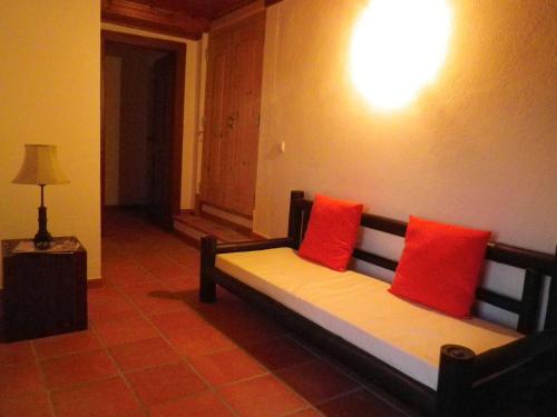 a couch with two red pillows in a room at Quinta de São José dos Montes in Ferreira do Zêzere