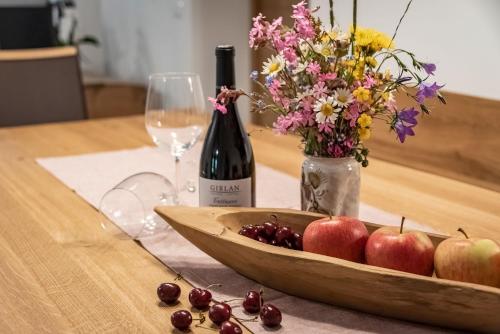 a table with a bottle of wine and a bowl of fruit at Blasighof in Quinzo