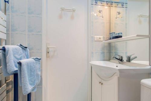 ein weißes Badezimmer mit Waschbecken und Spiegel in der Unterkunft Les Volets Bleus in Pornic