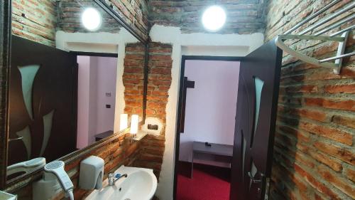 a bathroom with a brick wall and a sink and a mirror at Pensiunea SADA in Făgăraş