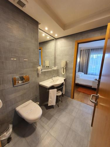 a bathroom with a toilet and a sink and a bed at Hotel Sunny Hill in Cluj-Napoca