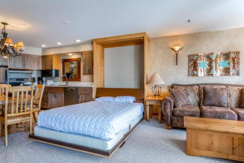 a bedroom with a bed and a couch and a kitchen at Shoshone 1972 in Big Sky Mountain Village