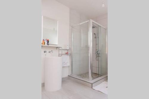 a glass shower in a bathroom with white walls at Maison des Paquerette in Mahébourg