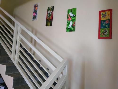 a white staircase with three paintings on the wall at Villa Gumilang in Batu