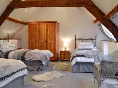 a bedroom with three beds and a wooden cabinet at The Granary in Swansea