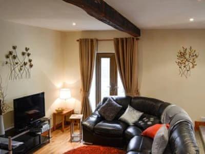 a living room with a leather couch and a television at The Granary in Swansea