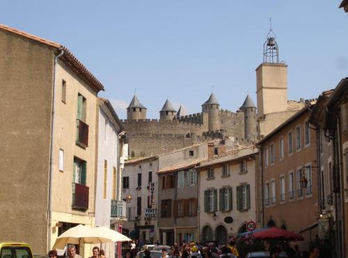 un groupe de personnes marchant dans une rue avec un château dans l'établissement Au pied de La Cité, piscine, vue extraordinaire, gîte La Trivala, à Carcassonne