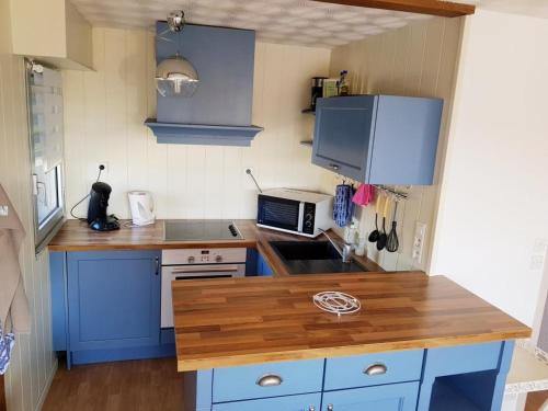 a kitchen with blue cabinets and a wooden counter top at Appartement sur le port du Crotoy vue Baie de Somme in Le Crotoy