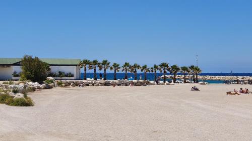 a beach with palm trees and people on the sand at Appartement T3 8eme Marselle St Anne Proche plage in Marseille