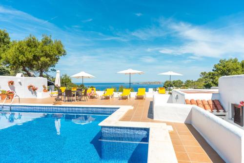 a swimming pool with a view of the ocean at Hostal Cala Moli in Cala Tarida