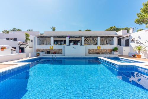 een villa met een zwembad en een huis bij Hostal Cala Moli in Cala Tarida
