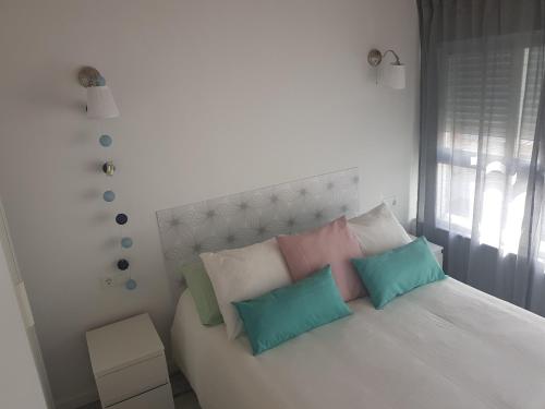 sypialnia z białym łóżkiem i kolorowymi poduszkami w obiekcie APT 6 - Apartamento en la playa de El Palo w Maladze