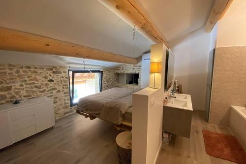 ein Schlafzimmer mit einem Bett und einem Waschbecken in einem Zimmer in der Unterkunft Charmante maison face à l’église de CODOLET in Codolet