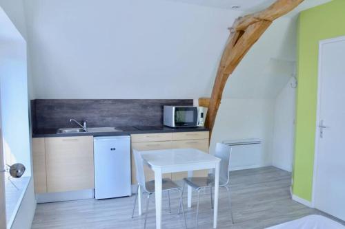een keuken met een witte tafel en een witte wastafel bij La petite maison appartement 2 in Avoine