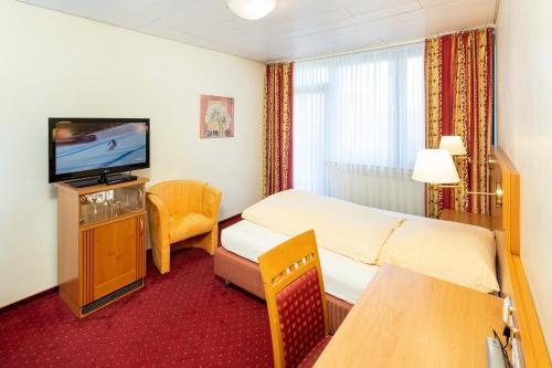 Habitación de hotel con cama y TV en Hotel Storck en Bad Laer