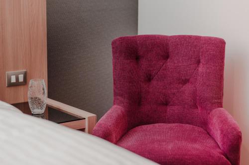 a purple chair in a room with a bed at Hotel Kavia Monterrey in Monterrey