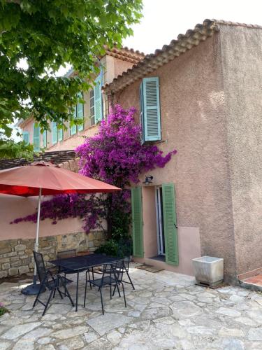 einen Tisch und Stühle mit einem Regenschirm vor einem Gebäude in der Unterkunft Petite maison au calme avec jardin clim et parking in Toulon
