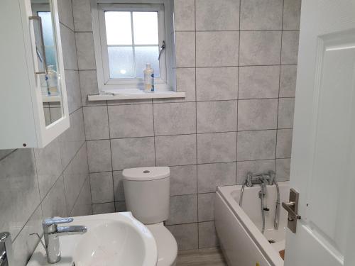 a bathroom with a toilet and a sink and a window at Barnfield Place in Edgware