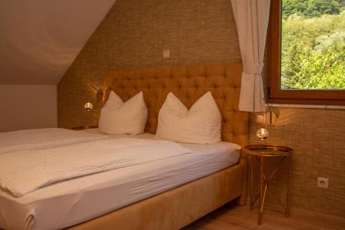 Un dormitorio con una cama con almohadas blancas y una ventana en Hotel-Restaurant Laux, en Merzig
