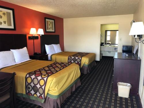2 Betten in einem Hotelzimmer mit roten Wänden in der Unterkunft Executive Inn & Suites Prescott in Prescott