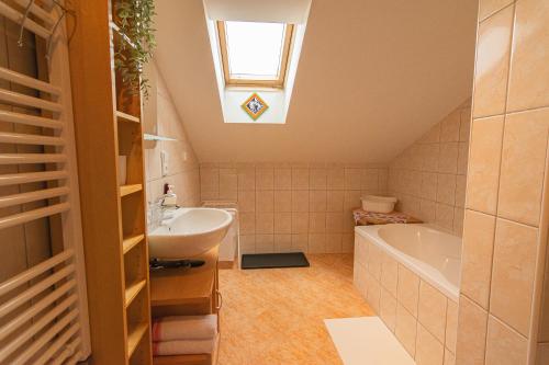 uma casa de banho com um lavatório, uma banheira e uma clarabóia em Apartman Charlie em Smržovka