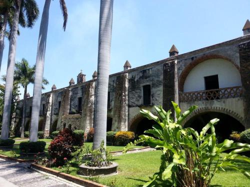 an old building with palm trees in front of it at Hotel Hacienda Vista Hermosa in Tequesquitengo