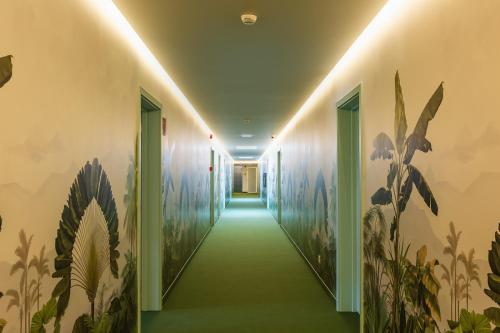 a hallway with a green carpet and paintings on the walls at Three House Hotel in Funchal