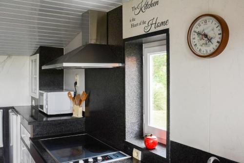 a kitchen with a clock on the wall and a sink at Chalet Den Keibilk in Heuvelland
