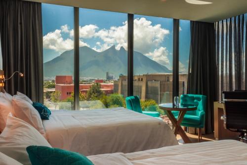 a hotel room with two beds and a view of a mountain at Hotel Kavia Monterrey in Monterrey