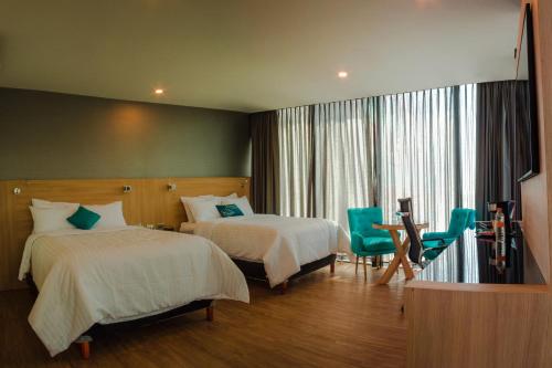 a hotel room with two beds and a window at Hotel Kavia Monterrey in Monterrey