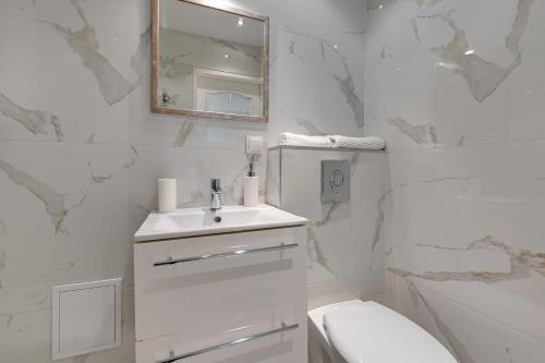 a white bathroom with a sink and a toilet at Merida Apartament in Sopot