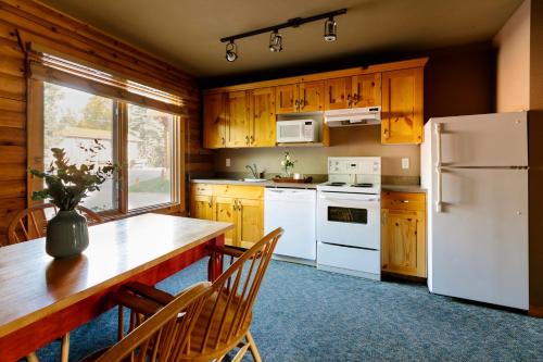 a kitchen with a stove, refrigerator and a table at Miette Mountain Cabins in Jasper