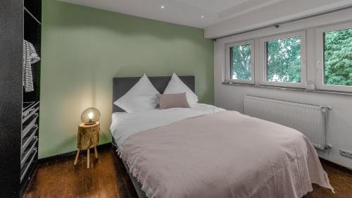 a bedroom with a white bed and a green wall at Das Wiesenhaus: Wohnen direkt am Rhein in Cologne