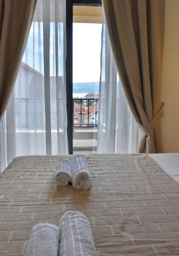 two towels on a bed in a bedroom with a window at Ralux apartman Tivat in Tivat