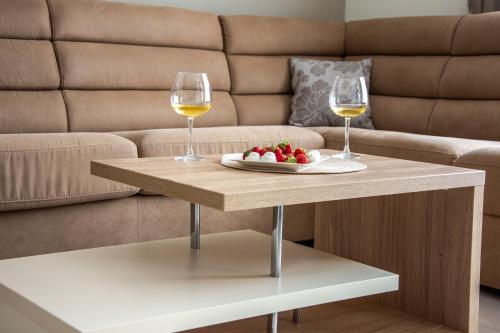 two glasses of wine and a plate of fruit on a coffee table at Ralux apartman Tivat in Tivat